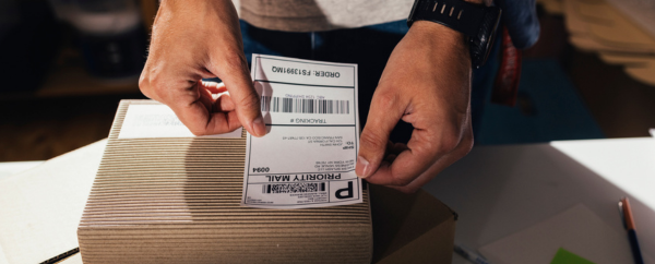 Closeup of man attaching shipping label to a package